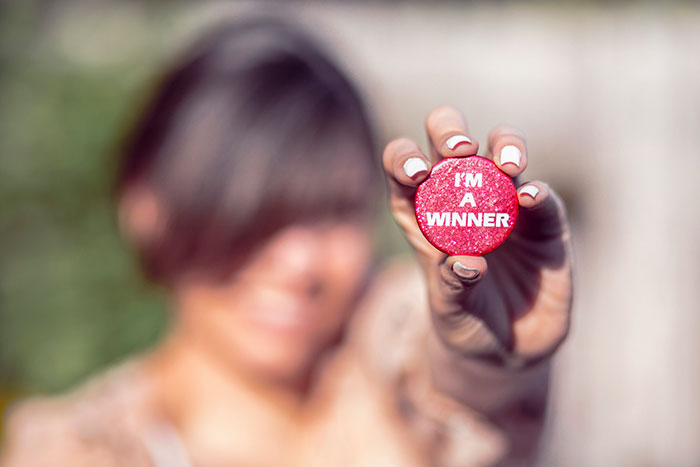 Una mujer sosteniendo un botón que dice soy un ganador.